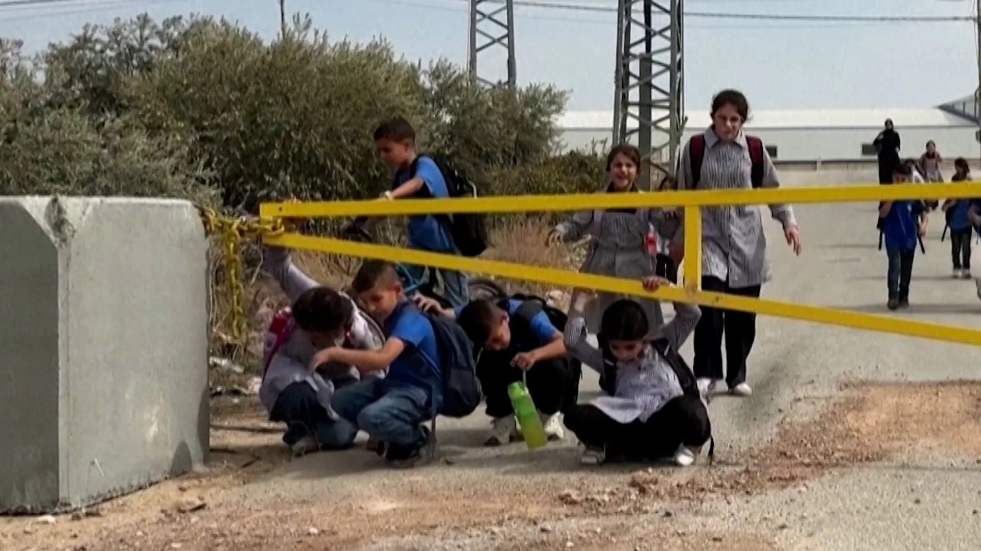 Palestinian children crawl under Israeli military gates to get to school